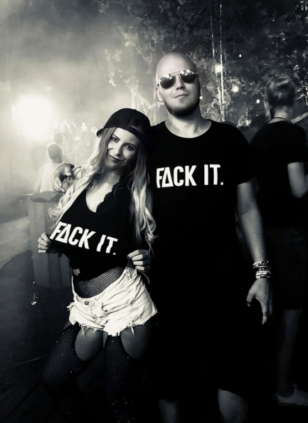Black Fack It T-Shirts with bold ‘Fack It’ logo on the front worn by a loving couple on a festival.