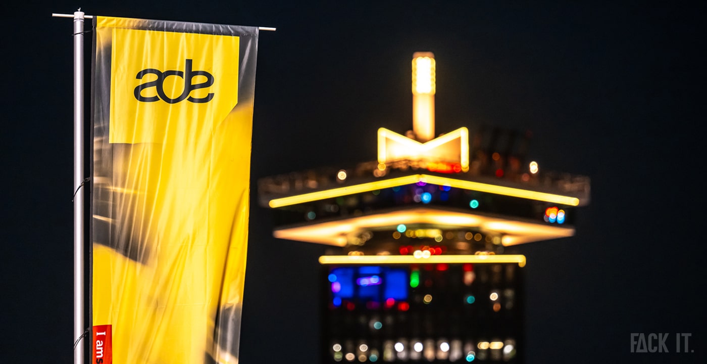 Amsterdam Dance Event 2025: The iconic A'DAM Tower lit up at night, with a vibrant crowd of music lovers gathering along the waterfront, celebrating the world's largest electronic music festival.