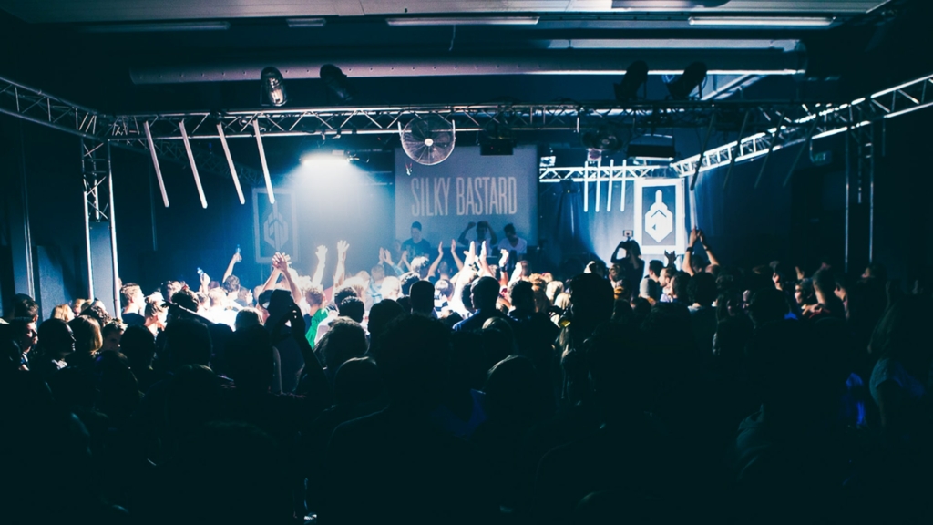 A euphoric crowd dances under flashing strobe lights in a dark club during a Fack It night in Tilburg.