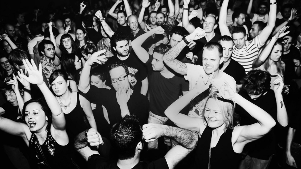 A euphoric crowd dances under flashing strobe lights in a dark club during a Fack It night in Tilburg.