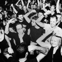 A euphoric crowd dances under flashing strobe lights in a dark club during a Fack It night in Tilburg.
