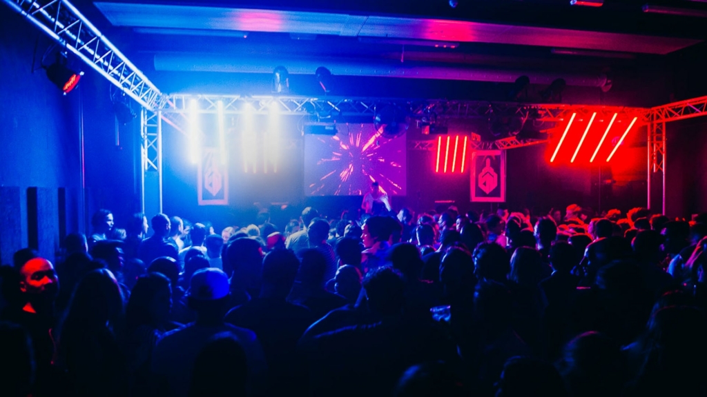 A euphoric crowd dances under flashing strobe lights in a dark club during a Fack It night in Tilburg.