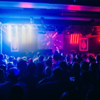 A euphoric crowd dances under flashing strobe lights in a dark club during a Fack It night in Tilburg.