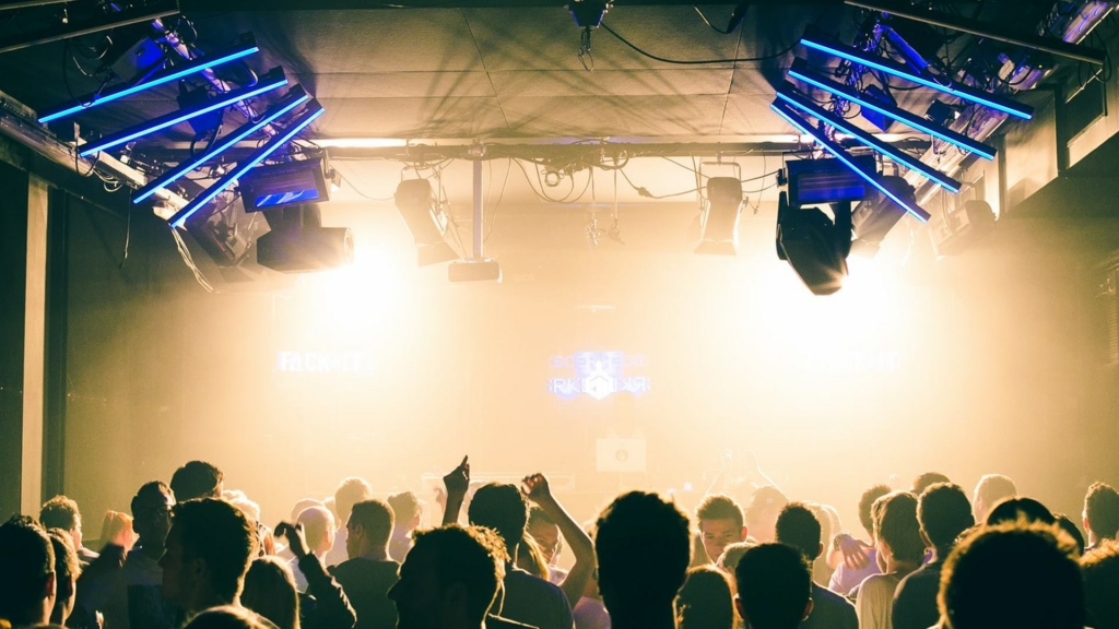 A euphoric crowd dances under flashing strobe lights in a dark club during a Fack It night in Tilburg.