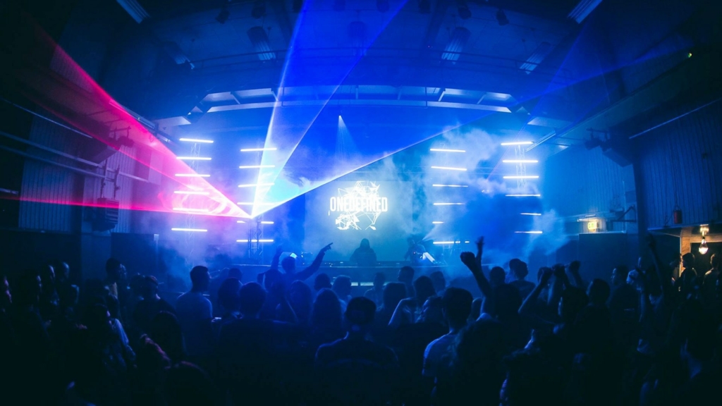 A euphoric crowd dances under flashing strobe lights in a dark club during a Fack It night in Tilburg.